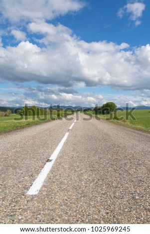 A road in the mountains under the sky with clouds and clouds, vertical picture