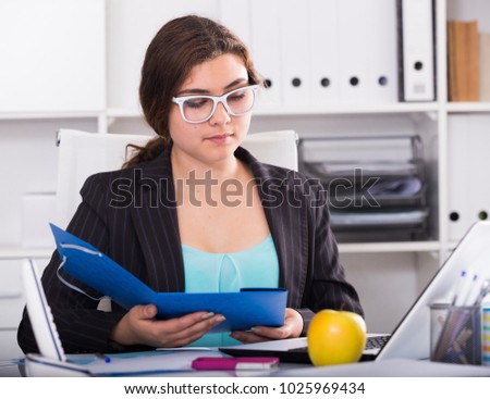 Young woman is reading documents before signing in office.