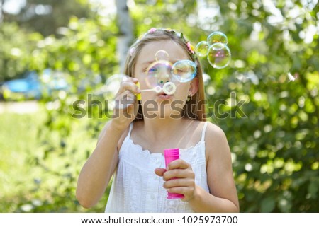Girl blows soap bubbles in the summer as a sign of transience