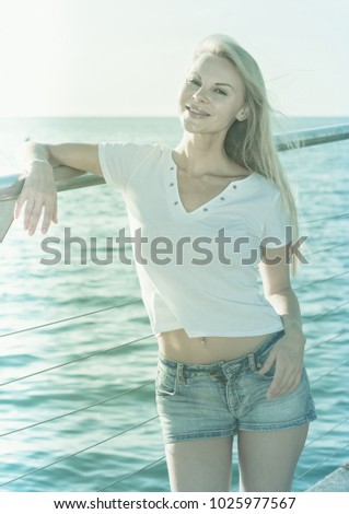 Female is posing on pirce in her free time near ocean.