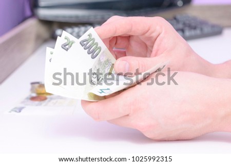 Close-up of a young man calculating Czech banknotes. A hand holding a stack of green money. Manual counting of money.