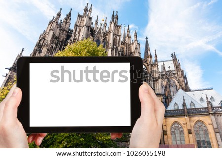 travel concept - tourist photographs Cologne Cathedral (Cathedral Church of Saint Peter) in Germany in september on tablet with cut out screen for advertising logo