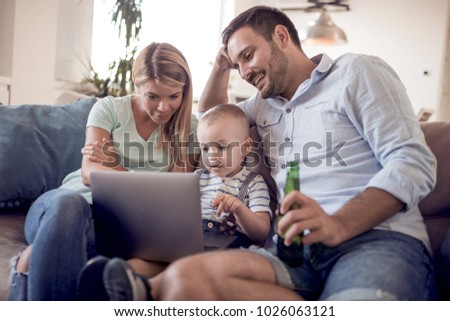 Portrait of a joyful family using a laptop ,sitting on sofa at home.