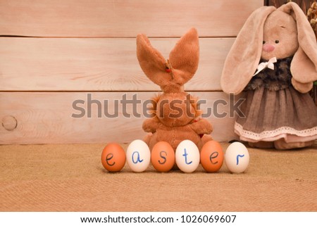 Easter picture. Toys are plush rabbits and chicken eggs. On the eggs the inscription with a blue marker - EASTER