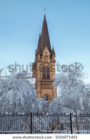 Roman catholic church with iron fence on blue sky background in winter time