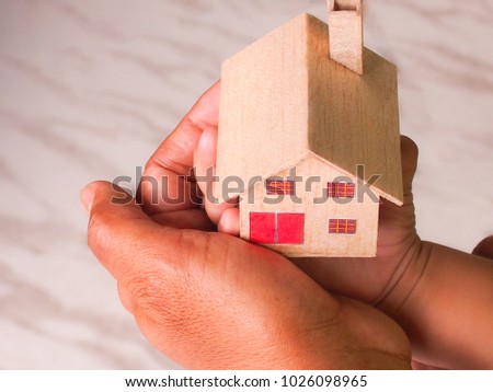Hands of adult and child holding house model.Home insurance concept.