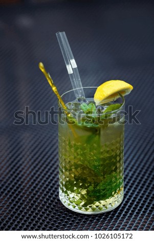 Mojito cocktail with lime and mint in highball glass on a grey table background. Copyspace