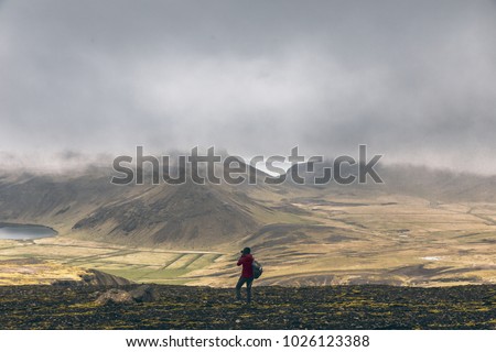 Icelandic landscape with woman taking picture for volcano
