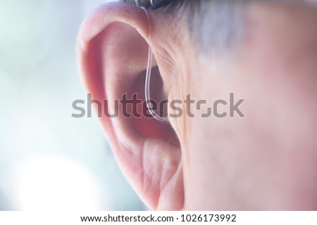 Modern digital in the ear hearing aid for deafness and the hard of hearing in aged man's ear. Royalty-Free Stock Photo #1026173992