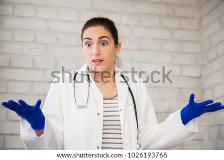 Portrait of the surprised young nurse who is standing indoors