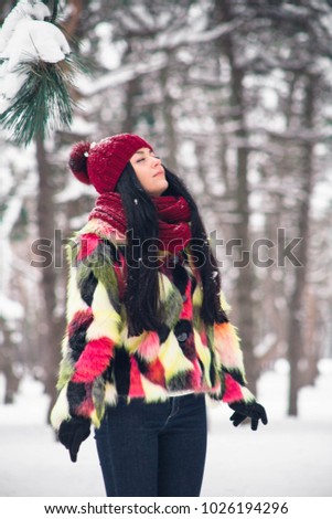 The girl is standing under a spruce branch