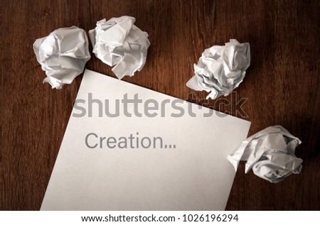 still life of paper and a crumpled paper on a table with an inscription creation
