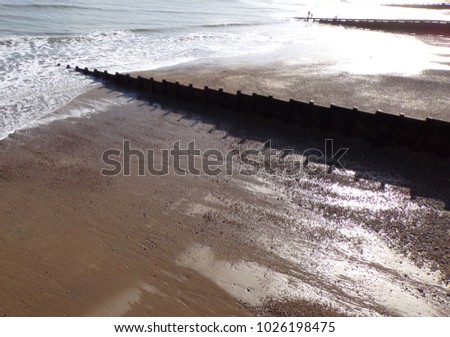 British seaside with wooden groynes for erosion prevention. Seascape background.