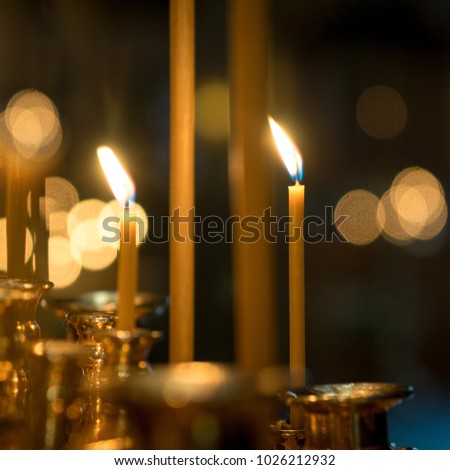 two burning candles in a Church on a dark background with blurred bokeh of the candles