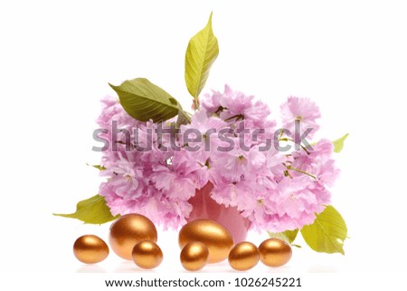 Big and small eggs in golden color for Easter near sakura flowers isolated on white background. Holiday and spring idea