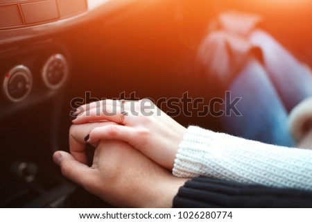 Loving couple holding hands in car. Close up shot of loving couple's hands, man and woman on travel road Royalty-Free Stock Photo #1026280774