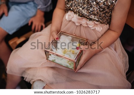 Wedding ceremony. A box with rings in the hands of a child. Pillow for rings. The girl is giving rings. Wedding rings on a flower. Wedding details.
