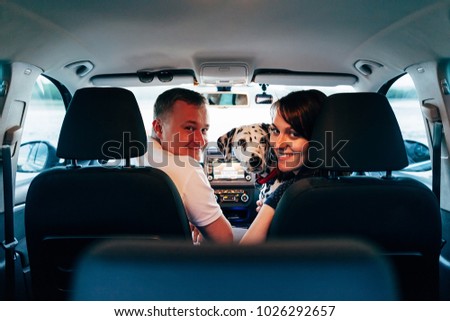 Portrait of happy young adult couple with dog on roadtrip. Man sitting on plaid with woman. Outdoor picnic concept.