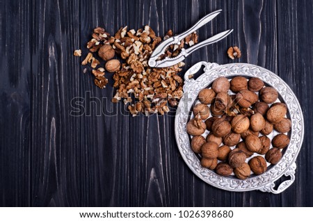 Walnut kernels and whole walnuts on a black wooden background. Top view Royalty-Free Stock Photo #1026398680