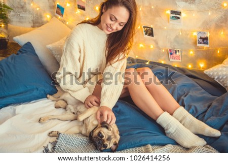 Young woman weekend at home decorated bedroom playing with dog