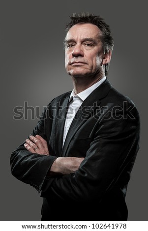Stern Imposing Business Man with Arms Folded in Suit on Grey Background Grunge Look Royalty-Free Stock Photo #102641978