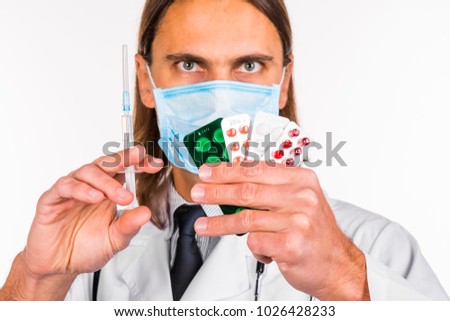 Portrait of a young friendly smiling male doctor dressed in beautiful uniform with stethoscope and medicine pills on abstract blurred white background. Healthcare medical and pharmaceutical concept