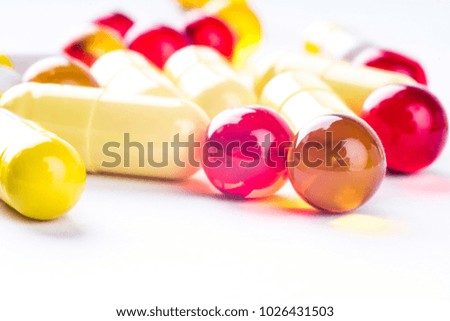 Colorful vitamin pills, medicine tablets and capsules on an abstract white background. Healthcare, medical and pharmaceutical concept. Detailed closeup studio shot with soft selective focus.