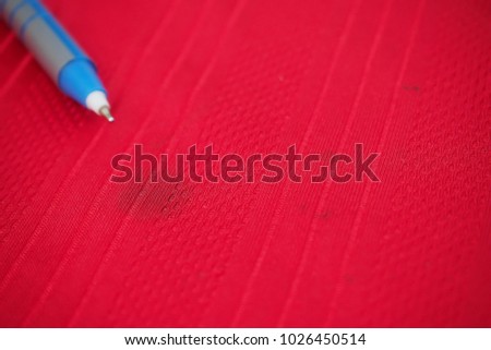 Blue ink stain from leaking pen on red shirt, daily life stain 
