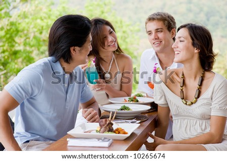 Four young adults enjoying a meal together on vacation Royalty-Free Stock Photo #10265674