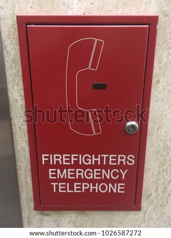 Firefighters emergency telephone red metal box mounted on office interior wall