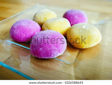Colourful Japanese Mochi in a transparent plate on wooden background.