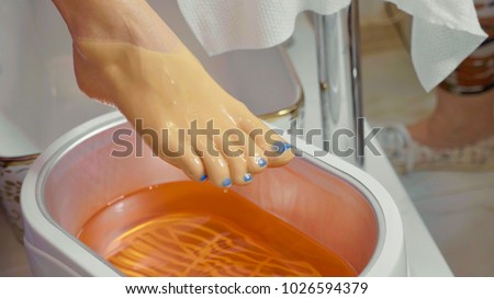 Wax bath for feet at beauty spa salon, close-up. Paraffin wax treatments for feet. Royalty-Free Stock Photo #1026594379