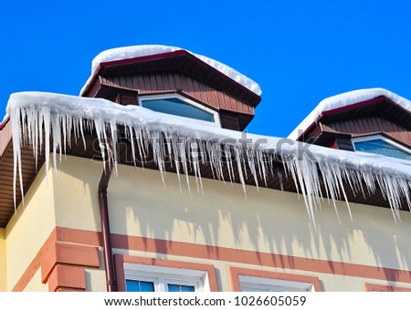 Icicles on the roof of the house on a Sunny day Royalty-Free Stock Photo #1026605059