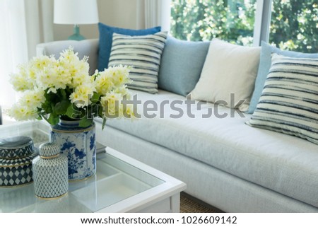 white flower in ceramic vase on table in  living room with navy blue pillows