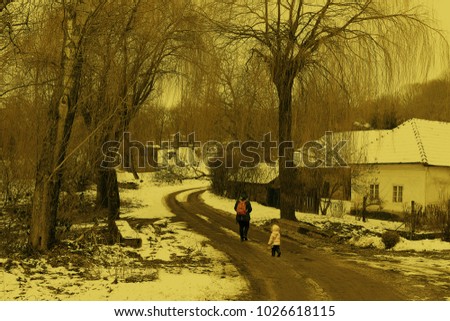 Ramble trough old village, sepia effect photography. Walking in old dorp in winter. Mother and doughter walking-up on the road under tall goat willows. Romantic ramble in old ham. Child in settlement