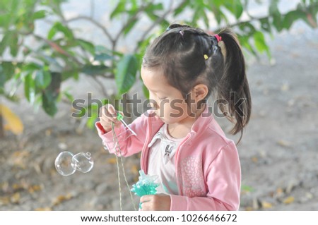 A little asian girl blowing soap bubbles