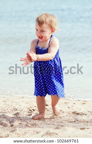 Happy toddler walking on sand beach