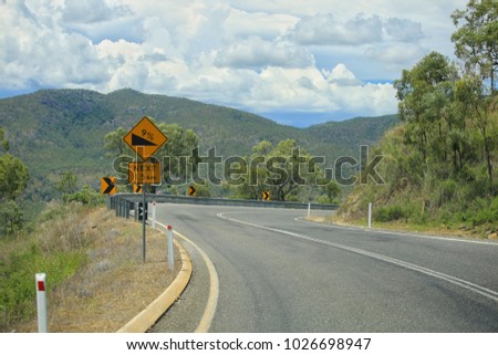 Twisting asphalt road in mountain. Yellow road signs attention dangerous turn, serpentine