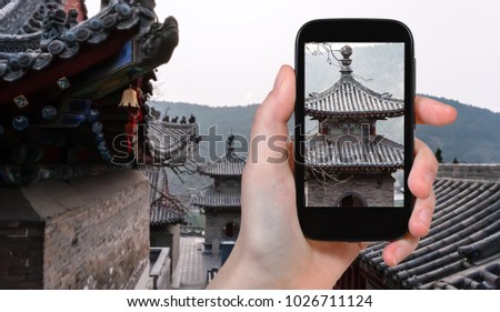 travel concept - tourist photographs Temples on East Hill of Chinese Buddhist monument Longmen Grottoes in spring evening on smartphone