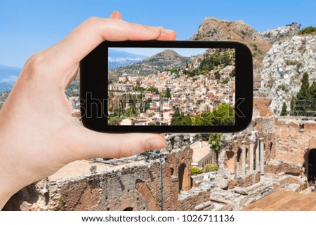 travel concept - tourist photographs Taormina city on slope of cape in Sicily Italy in summer on smartphone