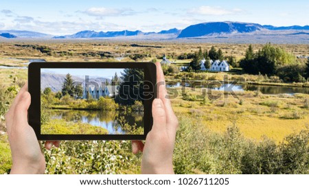 travel concept - tourist photographs rift valley in Thingvellir national park in Iceland in september on tablet