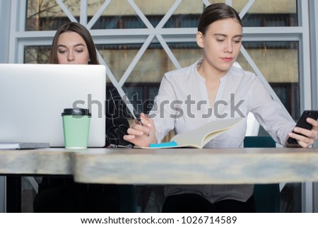 Woman skilled business planning writer reading notes on mobile phone during work process in office. Female financier analysing the market of company using cellphone. Business people collaboration 