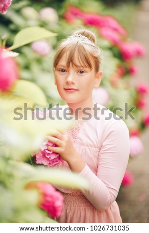 Portrait of adorable ballerina girl playing in hydrangea garden, wearing tutu dress and princess crown