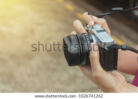 Tourist hold digital camera (mirrorless camera) ready for take a photo. Selective focus.