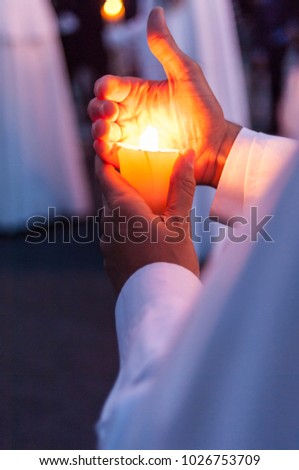 Detail of the hand of a penitent of the brotherhood of "La Paz" covering the flame of his candle so that it does not go out.