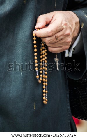 Detail of the hand of a penitent with a rosary, counting the beads while praying.