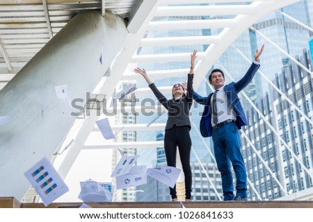Asian businessman and businesswoman throwing paper in the air and raising up two hands to cheerful and celebrated for successful in career and mission. concept of winner and competition.