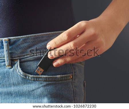 Young woman pushing usb flash drive into a jeans pocket Royalty-Free Stock Photo #1026872230