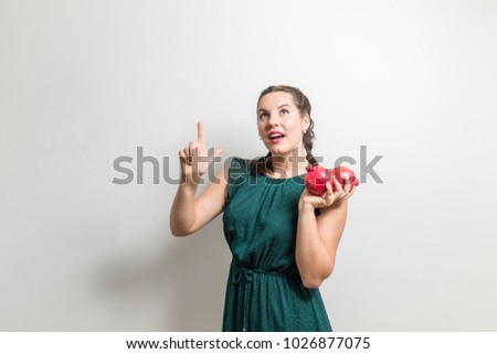 Nice woman points up with garnet fruits in hands