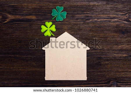 Lucky home symbol with four-leaf clover on wooden background. Copy space. St.Patrick's day holiday symbol. 